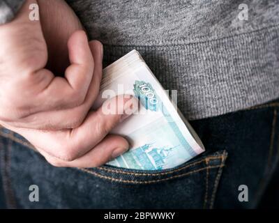 his hand put russian rubles in jeans pocket or take out from pocket Stock Photo