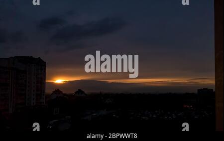 Sun bursting through the clouds above houses with countryside in the background Stock Photo