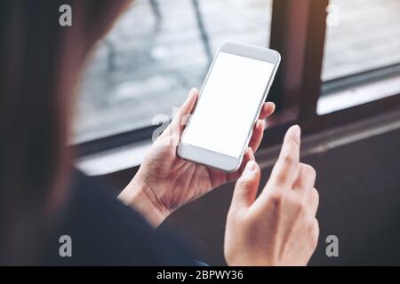 Mockup image of a woman holding white mobile phone with blank desktop screen in cafe Stock Photo