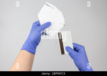 Hands with protective gloves holding a face mask and a credit card Stock Photo