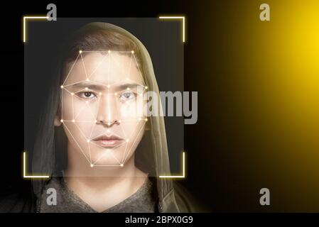Young asian man in black hoodie using face recognition over dark background. Modern technology concept Stock Photo