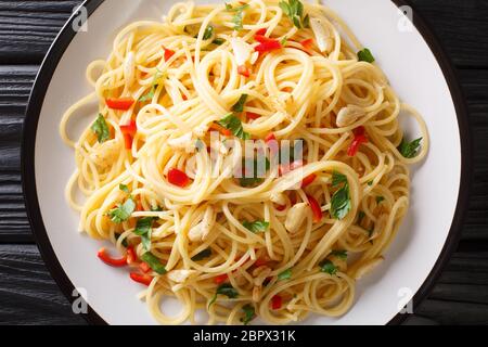 Italian food spaghetti Aglio e Olio with fried garlic, parsley and hot pepper close-up in a plate on the table. Horizontal top view from above Stock Photo