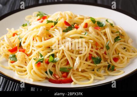 Spaghetti aglio e olio Italian for spaghetti with garlic and oil is a traditional pasta dish from Naples close-up in a plate on the table. Horizontal Stock Photo