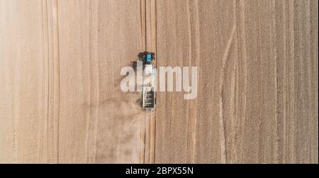 Aerial view of a blue tractor working in a field with a fertilizer and seed spreader Stock Photo