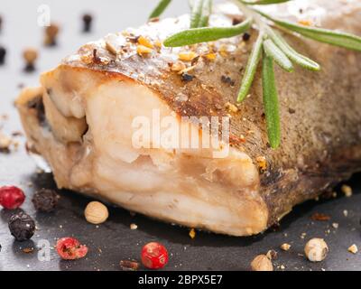 Steamed Fish with fresh rosemary and peppercorns close up on slate background. Healthy food. Stock Photo