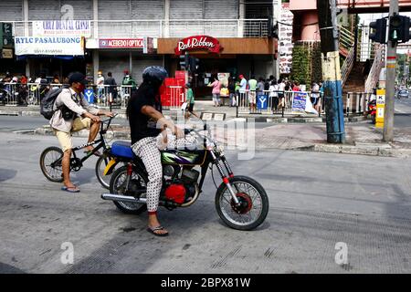 Antipolo City, Philippines - May 16, 2020: Motorcycle and bicycle riders wait for the green light at an intersection. Stock Photo