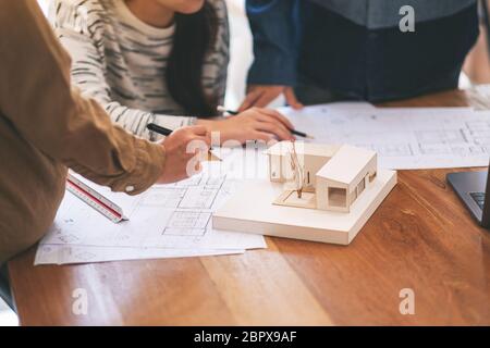 Group of an architect working and discussing about an architecture model together with shop drawing paper on table in office Stock Photo
