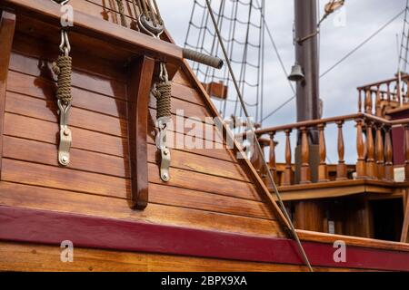 A historic sailing boat detail with ropes in a old vintage rustic wooden details. Warm tinted wooden materials creating a retro feeling Stock Photo