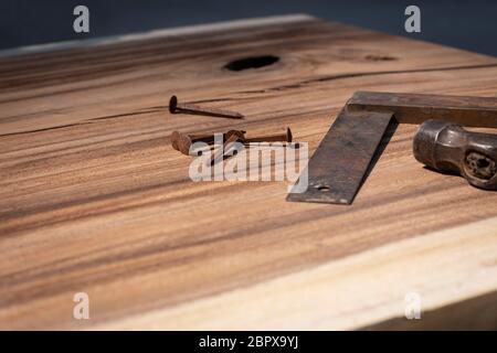 An old measuring tool, a part of a hammer and old rusty nails laying on a suar wooden slab. Vintage retro carpentry tools, diy Stock Photo