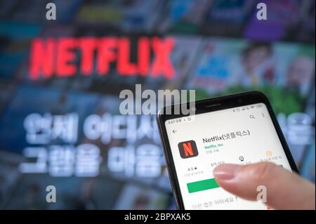 Seoul, South Korea - May 20, 2020: Hands to install the app with the Netflix screen and smartphone of the television. Stock Photo