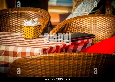 The cozy atmosphere of a small retro cafe with straw chairs and red tablecloth Stock Photo