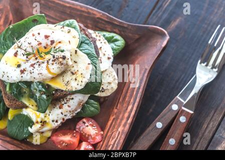 Sandwich with poached eggs, mozzarella, spinach and cherry tomatoes Stock Photo