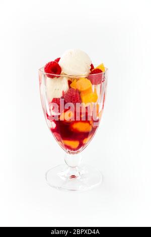 Vanilla ice cream with peaches, raspberries and raspberry sauce. Peach Melba isolated on white. Stock Photo