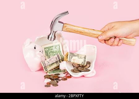 Men's hand smashes with a hammer Piggy bank on pink background. mockup, template. Concept of financial crisis after coronavirus covid-19 pandemic Stock Photo