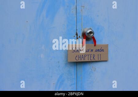 Cardboard sign with message SORRY, we are under CHAPTER 11, hanging on doorknob of closed door, many companies have financial problems due to covid-19 Stock Photo