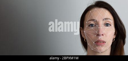 Facial recognition system, concept. Young woman on the grey background, face recognition Stock Photo
