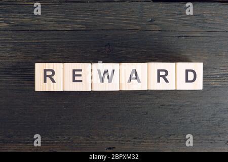 Word REWARD written on a wooden cube. Risk and reward concept Stock Photo