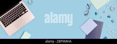 Flaylay of laptop and stationery on a blue pastel background. Workspace concept banner with place for text. Stock Photo