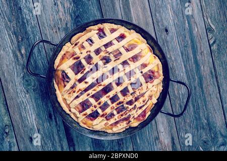 sweet pie in iron pan on wooden ground Stock Photo