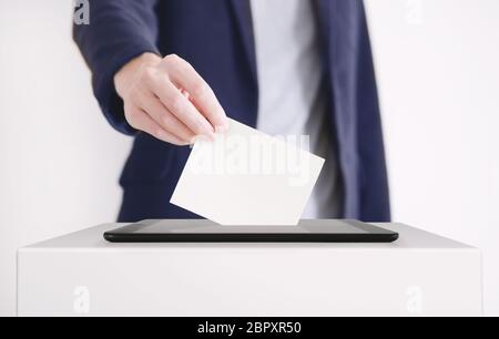 Businessman Putting a Ballot into a Digital Tablet. Voting Online Concept. Stock Photo