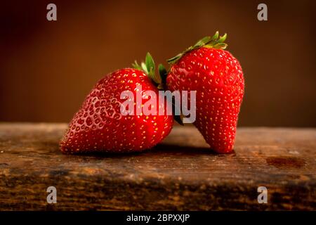 Two fresh juicy strawberries on a wooden surface Stock Photo