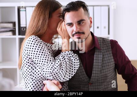 Woman gossip whispers in the ear of news to a man Stock Photo