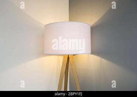 floor lamp standing near white grey wall with big lamp shade modern design, symmetrical light background texture close-up Stock Photo