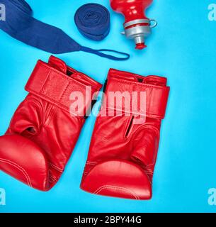 pair of red leather boxing gloves and a textile bandage on a blue background Stock Photo