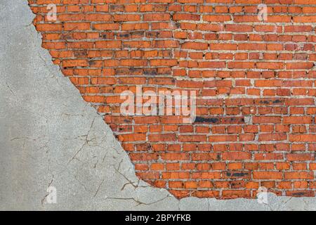old bad brick wall with leftovers of gray peeled thick sandy plaster Stock Photo