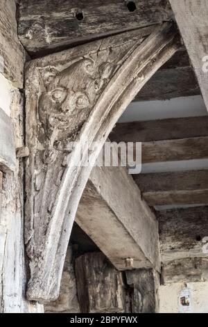 A 16c wood carving of a Green Man (or possibly a man smoking a tobacco pipe), on a corbel outside an old house in Presteigne, Powys, Wales, UK Stock Photo