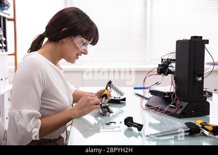 Female Engineer Or Tech Repairs Electronic Device In Hardware Repair Shop Stock Photo