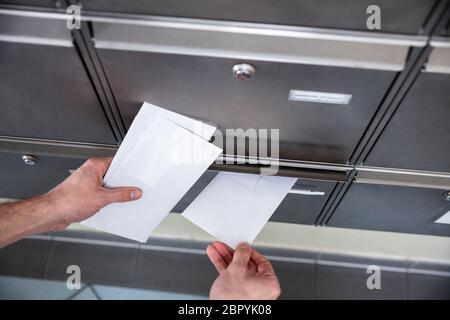 Close-up Of Man's Hand Inserting Letters In Mailbox Stock Photo