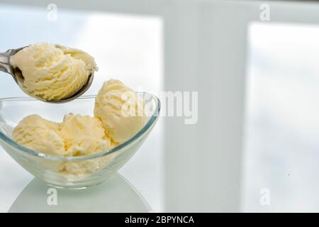a scoop of ice cream is placed in a glass bowl, place for text Stock Photo
