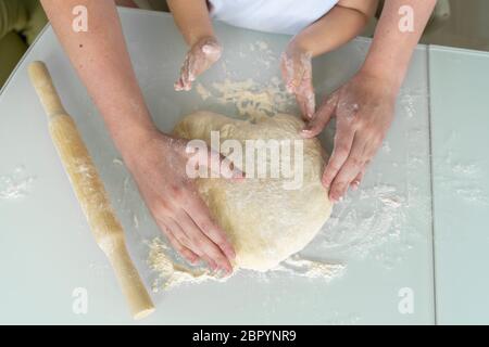 dad and baby sculpt a heart-shaped pie together, hands closeup, near a rolling pin. concept of love and family values Stock Photo