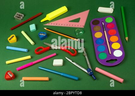 Different school supplies on green background, education or back to school concept. Stock Photo
