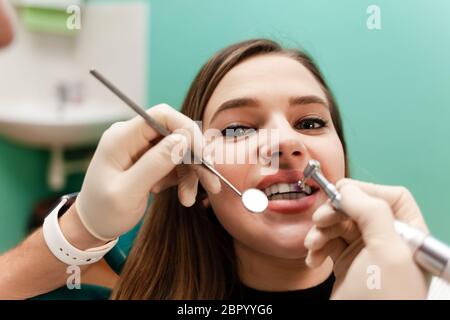 The doctor treats the patient's teeth with a drill close-up Stock Photo