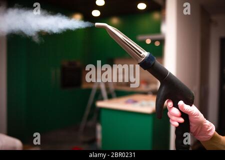 Closeup steam exiting nozzle of vapor cleaning machine at the hand Stock Photo