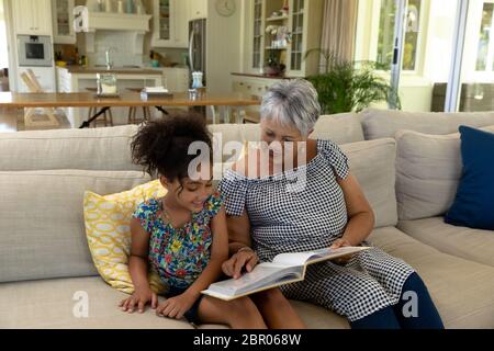 Senior mixed race woman reading with her granddaughter Stock Photo