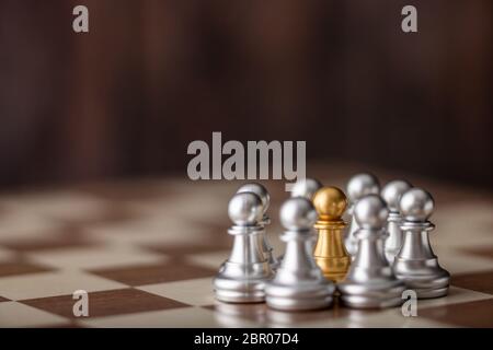 gold chessman standing in the midst on board with wooden background Stock Photo