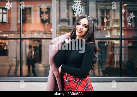 Portrait of a beautiful young girl in a christmas mood against the background of a window decorated with New Year decorations Stock Photo