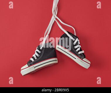 pair of black old textile sneakers  on a red background Stock Photo