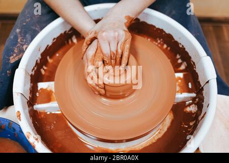Potter forms a clay jug. Process of creating ceramic products. Woman works on a pottery wheel Stock Photo