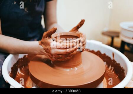 Woman is engaged in pottery. Potter in the process of creating a clay product Stock Photo