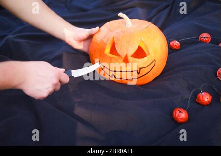 Hand cutting an orange pumpkin with a knife. Stock Photo