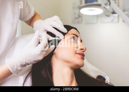 Cosmetologist makes anti-aging injections for her patient. Woman takes care of herself and does rejuvenating facial injections Stock Photo