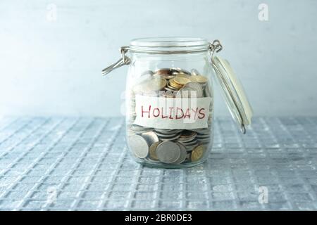 Coins in glass money jar with holidays label, financial concept. Stock Photo