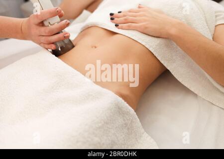 Doctor makes a vacuum massage procedure of the abdomen. Anti- cellulite body correction treatment Stock Photo