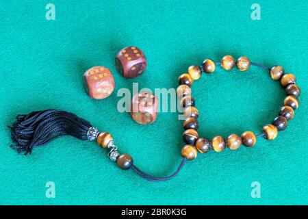 worry beads (komboloi) and three wooden dices with six points on green baize table Stock Photo
