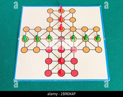 setup of cross solitaire board game on green baize table. The first mention of peg solitaire game can be identified in France in 1697 Stock Photo