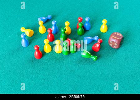 wooden dice and multicolored board game pawns on green baize table Stock Photo